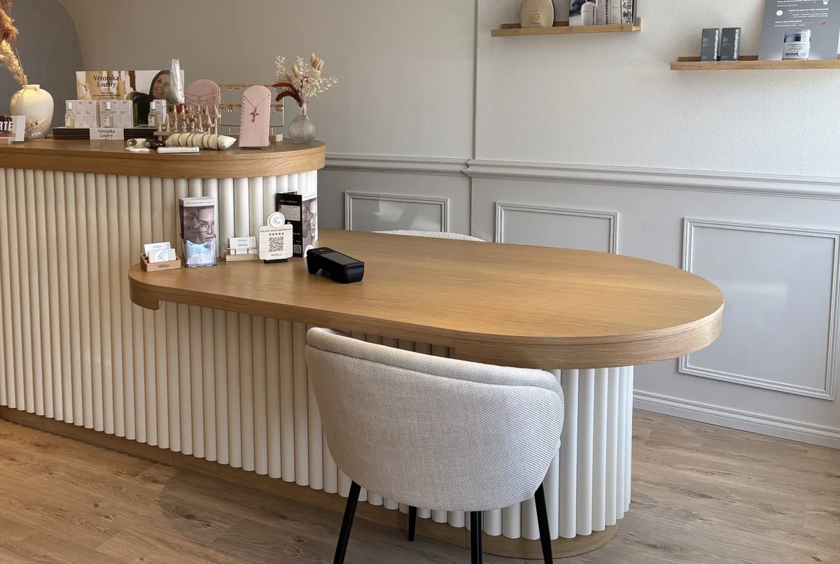L’accueil : comptoir cannelé, bureau en bois, produits Dermalogica et parfums