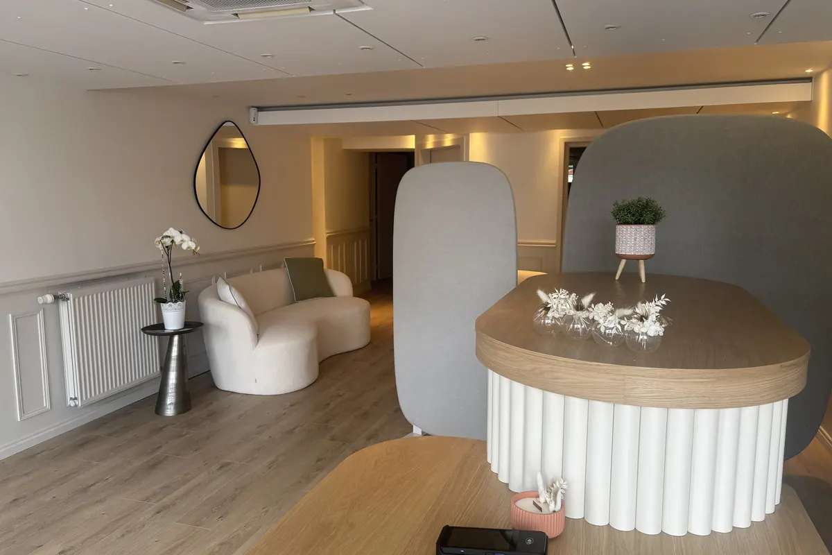 Le comptoir garni de fleurs séchées, le miroir rond et le canapé courbe en arrière-plan
