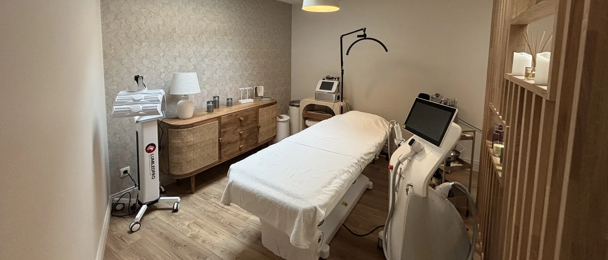 Vue large d’une cabine de traitement, table au centre et appareil laser à droite
