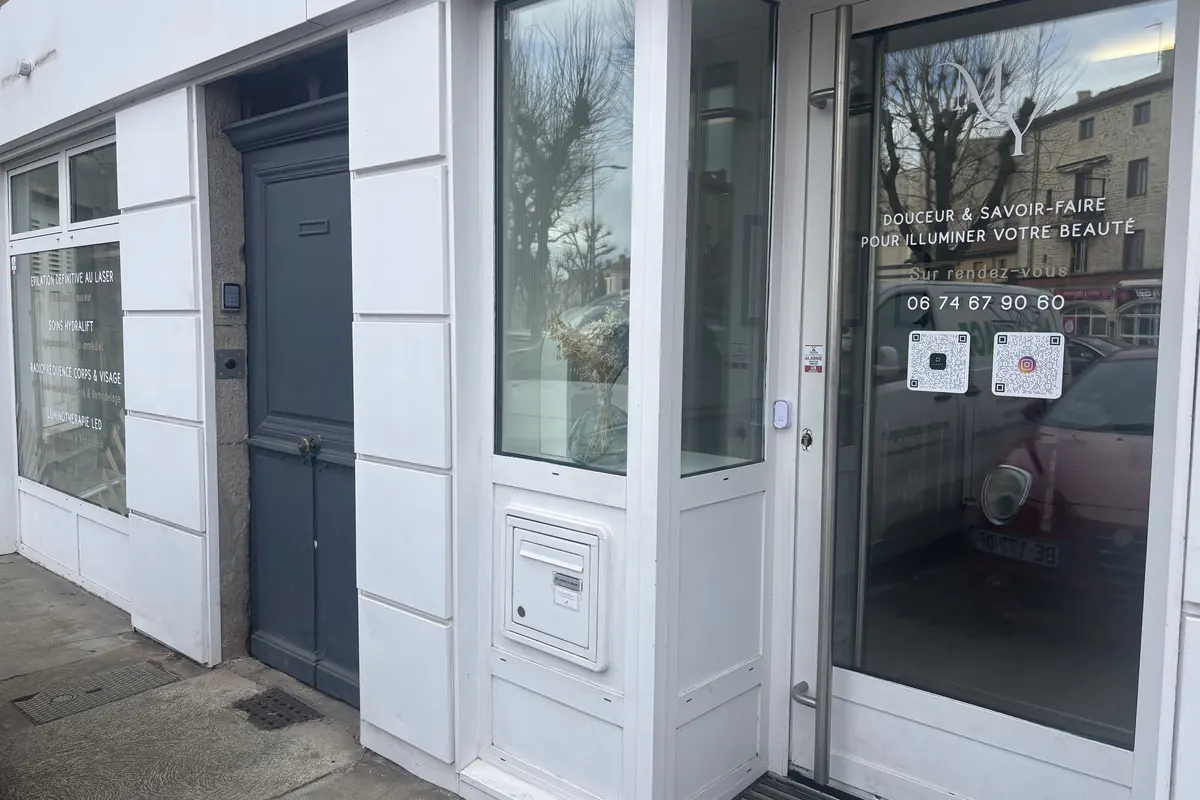 L’entrée de l’institut depuis le trottoir : porte vitrée et devanture blanche