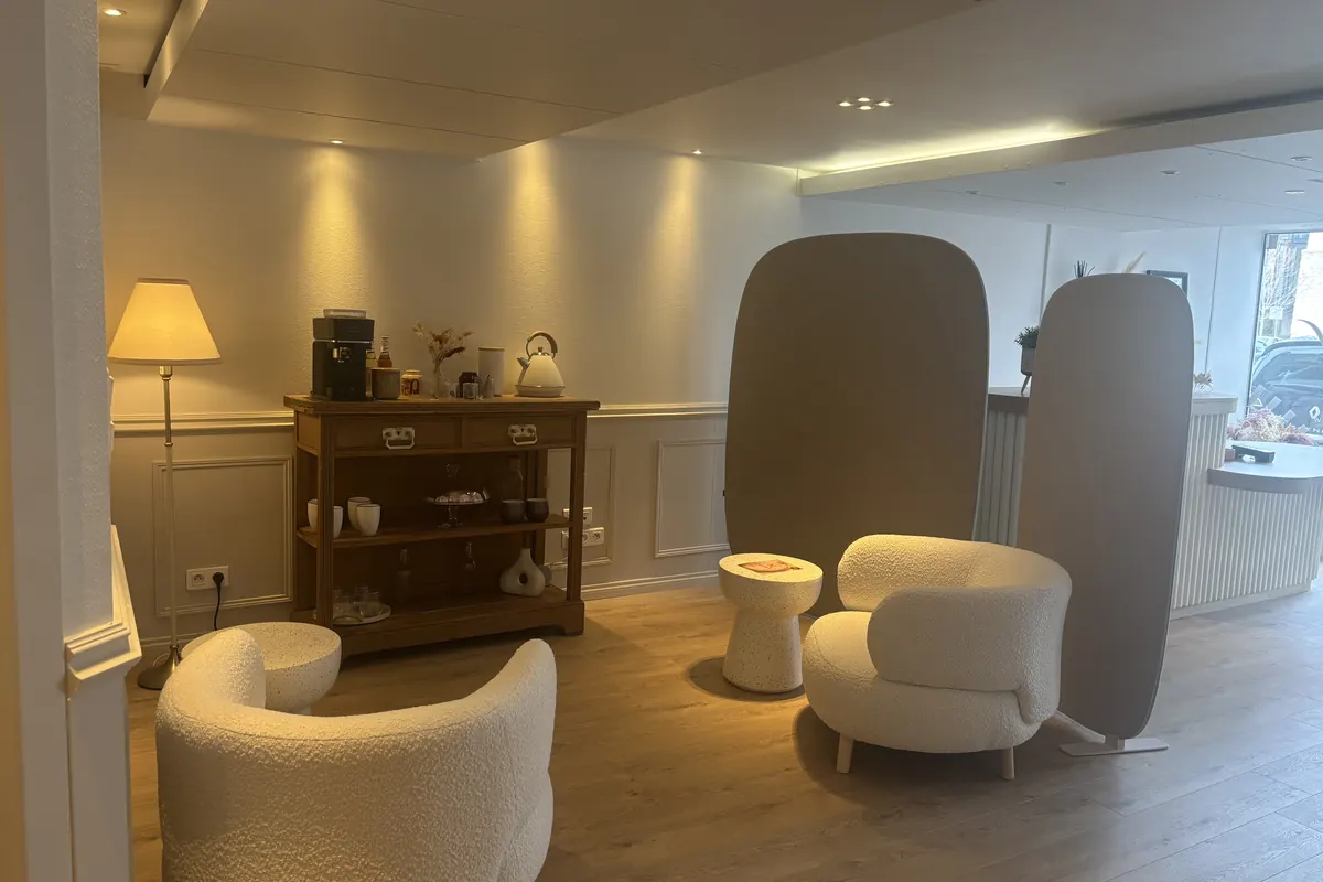 Deux fauteuils bouclette et la console à café, sous une lampe à abat-jour